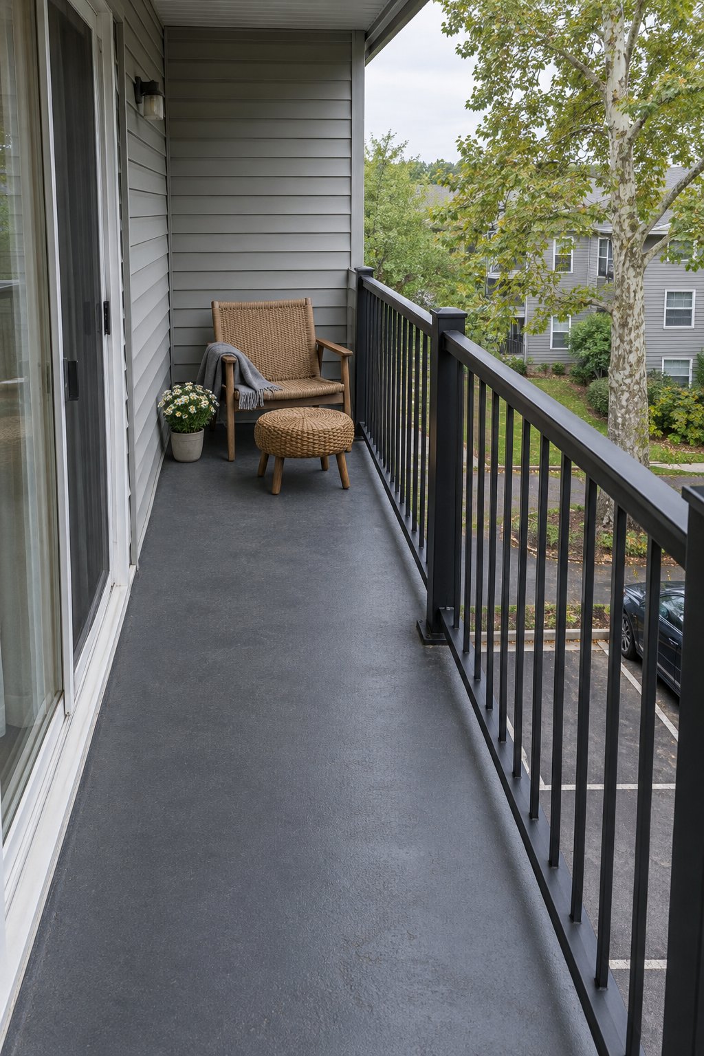 Small balcony ideas for apartments, one low outdoor chair and a round footstool at one end of a narrow balcony with a clear walkway to the sliding door